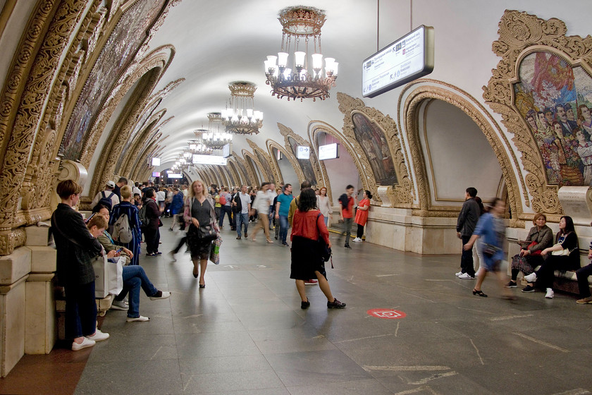 Interior, Kievskaya Metro station 
 The incredible interior of Kievskaya Metro station is seen during the evening commuter period with Moscovites rushing to get home. It is an interchange station on the circular Koltsevaya line that connects with the Arbatsko-Pokrovskay and Filyovskaya lines. Despite appearances, it is not that old being opened on 14th March 1954 following a competition held in Ukraine with the winning design out of seventy-three applicants submitted by E. I. Katonin, V. K. Skugarev, and G. E. Golubev. The design features 'low, square pylons faced with white marble and surmounted by large mosaics by A.V. Myzin celebrating Russo-Ukrainian unity. Both the mosaics and the arches between the pylons are edged with elaborate gold-coloured trim'. It's not quite the Northern Line is it? 
 Keywords: Interior Kievskaya Metro station