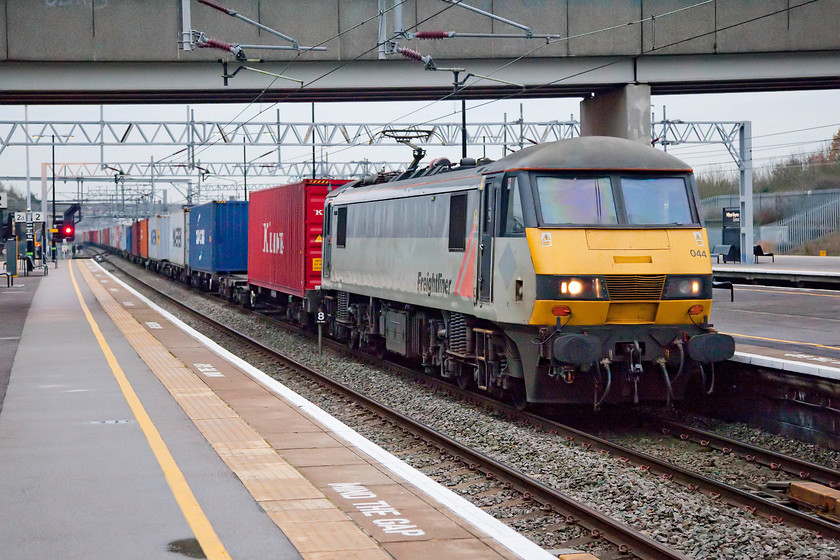 90044, 09.32 Felixstowe-Crewe Basford Hall (4M88), Milton Keynes station 
 I am asking a lot of the camera by this stage in the late afternoon at Milton Keynes station. In very poor lighting, 90044 passes at speed with the 09.32 Felixstowe North to Crewe Basford Hall Freightliner that was running quite late. Its speed necessitated a fast shutter speed so the ISO had to be ramped up to 1600. The excellent Photoshop plug-in, Neat Image, had to be called upon to clear up some noise issues. 
 Keywords: 90044 09.32 Felixstowe-Crewe Basford Hall 4M88 Milton Keynes station