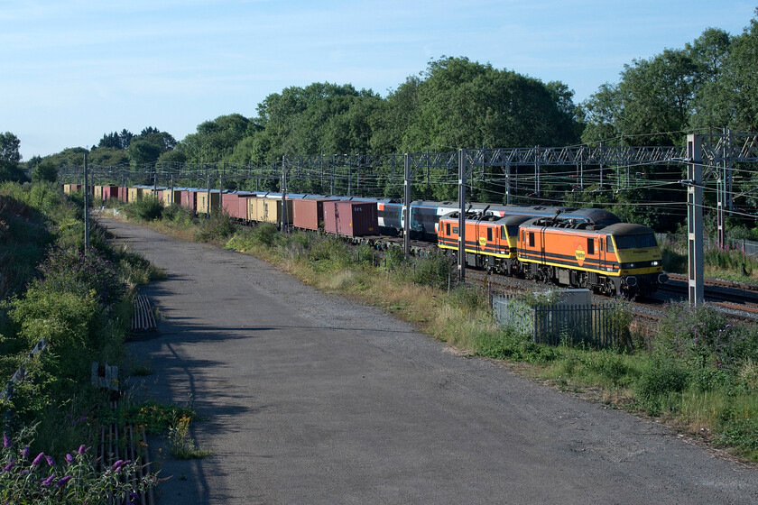 90015 & 90006, 02.57 Felixstowe North-Garston (4M45, 53E), site of Roade station 
 As a Class 390 Pendolino heads south at the site of Roade's former station the 4M45 02.57 Felixstowe to Garston Freightliner heads north lead on this day by 90015 and 90006 'Modern Railways Magazine/Roger Ford'. The latter is the only former Greater Anglia Class 90 that moved to Freightliner during 2020 to retain its original name with them more normally retained by the locomotives' owners, in this case, Porterbrook. I think that the Genesee & Wyoming orange livery applied to most of Freightliners' Class 90s looks smart and brings them another lease of life, ironically back on the same tracks that they were introduced to service on back in the late 1980s. 
 Keywords: 90015 90006 02.57 Felixstowe North-Garston 4M45 site of Roade station Freightliner