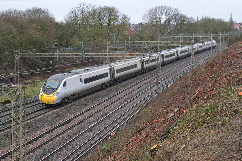 390045, VT 07.05 Wolverhampton-London Euston (1B05, 8L), Ashton Road bridge 
 390045 passes Ashton Road bridge just south of the village of Roade in Northamptonshire working the Avanti West Coast 07.05 Wolverhampton to Euston service. Whilst the Pendolino is partially obscured by the wiring, I am taking full advantage of this totally new view following recent clearance of the embankment in order to undertake stabilisation work. 
 Keywords: 390045 07.05 Wolverhampton-London Euston 1B05 Ashton Road bridge Avanti West Coast Pendolino