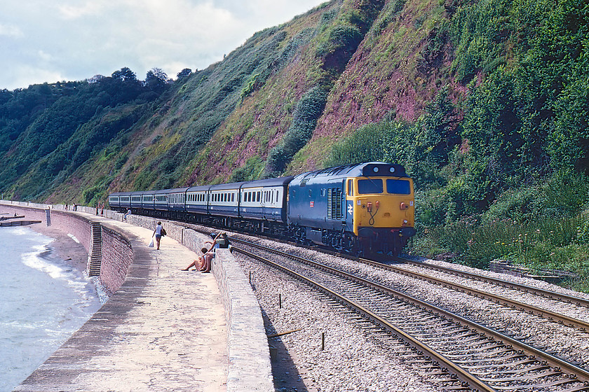 50012, 09.50 Penzance-London Paddington, Parson`s Tunnel 
 Looking very smart in the summer sunshine, 50012 'Benbow' brings the 09.50 Penzance to London Paddington along the seawall. It is just approaching Parsons Tunnel. The base of the old Parsons Tunnel signal box, that closed in 1964, can be seen at the base of the cliff. What a smashing spot this must have been to be a signalman. When I visited this spot nearly forty years later, the scene was remarkably similar but the subject matter was very different with an entire generation of motive power, the HSTs, having been jumped!...... https://www.ontheupfast.com/v/photos/21936chg/24745332404/x800003-800004-12-47-penzance-north 
 Keywords: 50012 09.50 Penzance-London Paddington Parson`s Tunnel