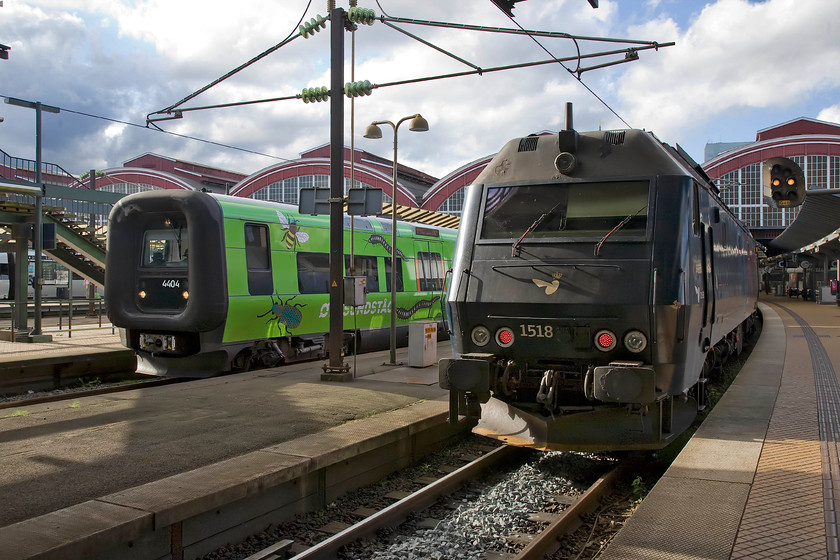 4404, 17.20 Copenhagen Central-Helsingborg & 1518, 16.16 Holbk-sterport, Copenhagen Central station 
 Wearing its distinctive vinyls DSB Class ET set 4404 makes ready to leave Copenhagen Central with the 17.29 to Helsingborg, a Swedish town north of Malmo. This unit was built by Bombardier in 2011 and is owned by Transitio AB a Sweedish multi-transport procurement and leasing company. As part of its journey, this unit will use the impressive resundstg bridge and tunnel to reach Sweeden, it wears the branding of the same name on its flanks. To the right of the Sweedish service is 1518 at the rear of the 16.16 Holbk to sterport train. This locomotive is one of a handful of the ME class that are 'tunnel approved' meaning they too can operate resund services to Sweden as per the Class ET. 
 Keywords: 4404, 17.20 Copenhagen Central-Helsingborg & 1518, 16.16 Holbk-sterport, Copenhagen Central station DSB Class ME DSB ET