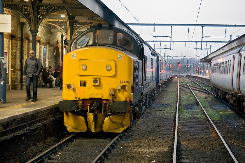 37425, LE 15.48 Lowestoft-Norwich (2J83), Norwich station 
 A proper train arrives at Norwich station! 37425 'Sir Robert McAlpine' has just come to halt on platform two leading the 15.48 from Lowestoft. Being the first weekday after the clocks went back means by this time in the late afternoon it is getting pretty dark. Notice the neat reflection of the colour light on the face of the track of the centre siding. 
 Keywords: 37425 15.48 Lowestoft-Norwich 2J83 Norwich station DRS Direct Rail Services GA Greater Anglia Sir Robert McAlpine