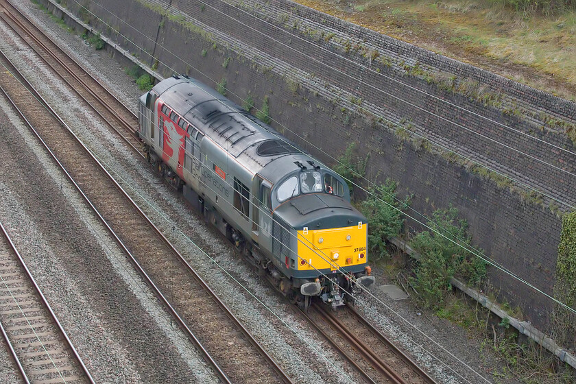 37884, 12.00 Derby RTC-Wembley Yard (0H72, 7E), Roade cutting 
 had spotted the path for a light engine on RTT when studying it for the forthcoming day as I do most mornings (I need to get a life really dont I!). Come its departure time nothing was showing on RTT so I suspected that it would not run, but suddenly, whilst eating my lunch, half an hour after its scheduled departure time it was off and running! Running now some twenty minutes late, 37884 Cepheus accelerates through Roade cutting running as 0H72, the 12.00 Derby RTC to Wembley Yard. I suspect that it will be involved in some sort of movement of a scrap train in the forthcoming week to Newport (Sims Group). 
 Keywords: 37884 12.00 Derby RTC-Wembley Yard 0H72 Roade cutting ROG Rail Operations Group Cepheus