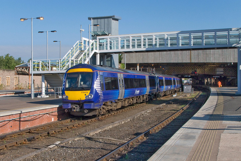 170478, SR 06.50 Inverness-Edinburgh Waverley (1B08), Perth station 
 170478 emerges into the glorious summer sunshine leaving Peth with the 1B08 06.50 Inverness to Edinburgh. The train is passing under the station new footbridge that opened in 2013 at a cost of one million pounds. It has just been awarded the 2015 Carbuncle Award which recognises the worst planning decisions taken throughout the UK. The bridge, as well as being totally out of character with the rest of the superb Victoria station, is inconveniently located and simply duplicates other footbridges around the station. Whilst the vast majority of passengers will not use it as it will involve an unnecessary and convoluted walk around the station it does provide full disability access for those with particular needs. However, why this provision could not be provided within the existing structures at a fraction of the cost remains a mystery? 
 Keywords: 170478 06.50 Inverness-Edinburgh Waverley 1B08 Perth station ScotRail