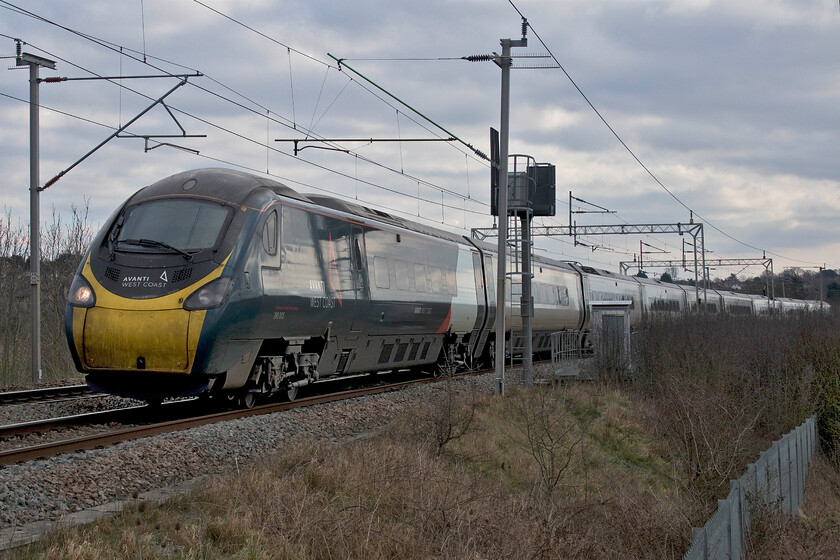 390005, VT 10.50 London Euston-Liverpool Lime Street (1F15, 1L), Wilson's Crossing 
 Due to repairs to a semi-collapsed embankment on the western side of the down fast line at Hillmorton Junction all down services have been diverted through Northampton with a severe TSR on the up line in place but, at least, that route has remained open. 390005 'City of Wolverhampton' picks up speed away from Northampton past Wilson's Crossing working the diverted 10.50 Euston to Liverpool 1F15 service. Avanti appears to have been struggling to keep its fleet looking smart as in the case of 390005 with a distinctly dirty front end. Perhaps its carriage washers have been frozen up recently with the week of sub-zero temperatures throughout most of the county? 
 Keywords: 390005 10.50 London Euston-Liverpool Lime Street 1F15 Wilson's Crossing Avanti West Coast Pendolino City of Wolverhampton