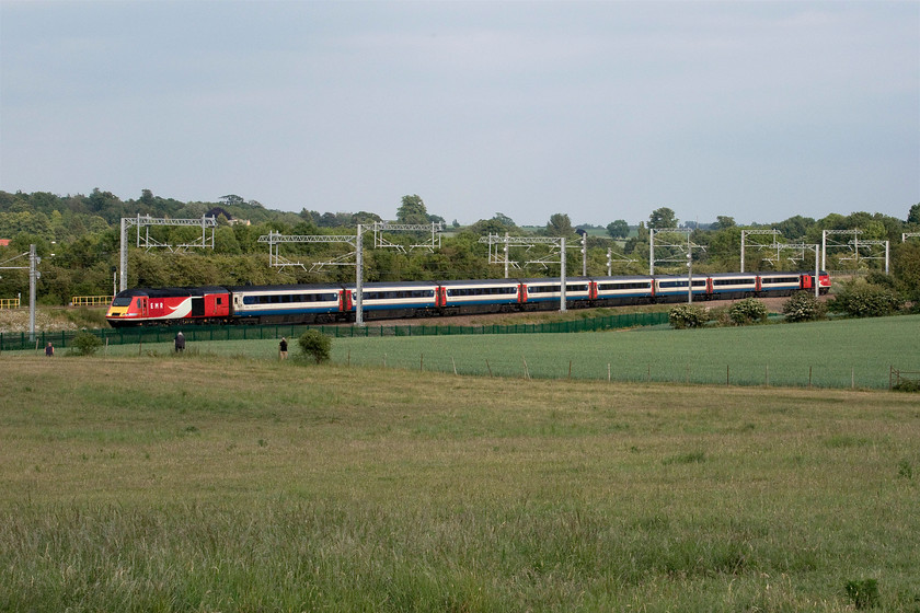 43257 & 43307, EM 18.34 London St. Pancras-Nottingham (1D64, RT), Irchester SP927667 
 MML or ECML? The 18.34 London St. Pancras to Nottingham passes the fields at Irchester south of Wellingborough made up of a set of EMR branded stock with two former LNER power cars, 43257 and 43307, at either end. I have not been to this location since the dreaded palisade fencing has been installed. However, things could be a whole lot worse as the green variant has been chosen as opposed to the far more conspicuous silver type. The green fencing blends far better with the lush greenery of the early summer fields. Note the three enthusiasts waiting at the field boundary for the train following along behind...... https://www.ontheupfast.com/p/21936chg/29180054004/x0010-57310-91128-90035-82136-47813 
 Keywords: 43257 43307 18.34 London St. Pancras-Nottingham 1D64 Irchester SP927667 Virgin East Coast LNER MML ECML East Midlands Railway