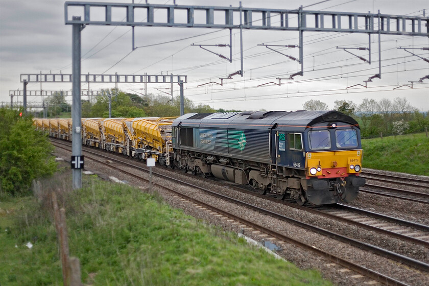 66419 Willesden Yard-Rugby HOBC (6Y60), Ashton Road bridge 
 In preparation for weekend engineering works the HOBC (High Output Ballast Cleaner) train is seen passing close to Roade as the 6Y60 Willesden Yard to Rugby train. GBRf's 66419 is leading the train with 66610 out of sight on the rear. Apologies for the poor technical quality of the image, the light was pretty dire by this stage in the early evening. 
 Keywords: 66419 Willesden Yard-Rugby HOBC 6Y60 Ashton Road bridge