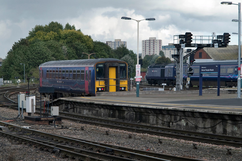 153373, stabled & class 43, GW 13.00 Bristol Temple Meads-London Paddington (1A18), Bristol Temple Meads station 
 153373 sits stabled in one of the bay sidings at the eastern end of Temple Meads station. In the background, a class 43 HST leaves, as it has done thousands of times, with, in this case, the 13.00 to London Paddington. Notice to the left of the class 153 the mechanical levers named as Bristol TM East GF. It's an amazing survival and one that I photographed from the reverse angle 41 years ago in 1977, see..... https://www.ontheupfast.com/v/photos/21936chg/23615765204/you-can-see-that-this-negative-has 
 Keywords: 153373 class 43 13.00 Bristol Temple Meads-London Paddington 1A18 Bristol Temple Meads station