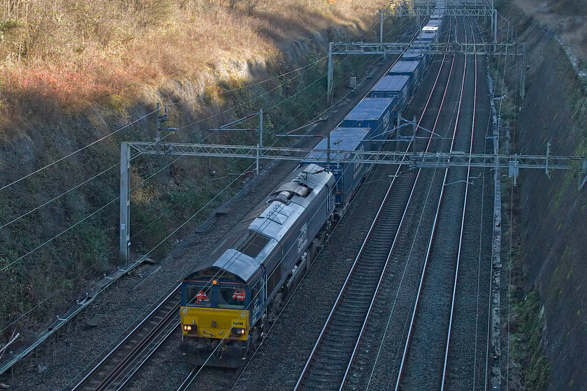 66108, 10.02 Tilbury FLT-DIRFT (4M07, 2E), Roade cutting 
 Despite it being lunchtime the depths of Roade cutting are already in full shade! Catching no sun at all, 66108 leads the 10.02 Tilbury to Daventry (DIRFT) DRS service. Notice, the hi-viz jackets of the train crew standing out in the cab of the Class 66. 
 Keywords: 66108 10.02 Tilbury FLT-DIRFT 4M07 Roade cutting DRS