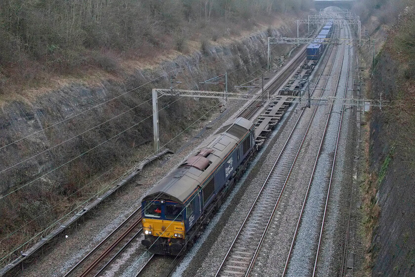 66426, 10.03 Tilbury-DIRFT (4M07, 19E), Roade cutting 
 This 4M07 10.03 Tilbury to Daventry was absolutely flying as it passed me heading north through Roade cutting! Freights normally trundle their way along the WCML at a relatively sedate pace with the locomotives working hard hauling their payloads. However, observation of this photograph reveals that today's 4M07 is extremely short with just ten boxes being hauled making for a particularly light load. With the driver eager to take advantage and get an early cup of tea on arrival at DIRFT the train's approach caught me off guard and found me having to ramp up the shutter speed at the last second to avoid motion blur! 
 Keywords: 66426 10.03 Tilbury-DIRFT 4M07 Roade cutting Tesco Express