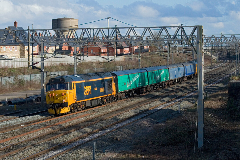 50049 & 50007, 14.49 Willesden TMD-Leicester LIP (5F69, 30E), site of Roade station 
 Returning to their Leicester base 50049 Defiance leads the 5F69 14.49 Willesden to Leicester LIP working. 50007 Hercules is just visible on the rear of the train being towed along for the ride. The working is returning a set of barrier and translator stock following its use in moving units around the network. The GBRf livery really looks smart on these heritage locomotives that I took many images of back in the early 80s in the West Country. 
 Keywords: 50049 50007 14.49 Willesden TMD-Leicester LIP 5F69 site of Roade station Defiance Hercules