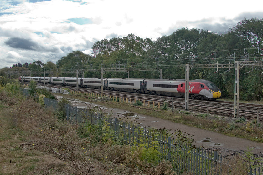 390011, VT 11.49 London Euston-Birmingham New Street (9G08, 4L), site of Roade station from former Pianoforte site 
 390011 'City of Lichfield' works the 11.49 Euston to Birmingham New Street past Roade. This location is on top of a bank built as part of a large housing estate occupying the former Pianoforte/Simplex site. An interesting location but one that is absolutely hopeless for the sun at this time of day, witness the lack of detail in the sky! 
 Keywords: 390011 11.49 London Euston-Birmingham New Street 9G08 site of Roade station from former Pianoforte site