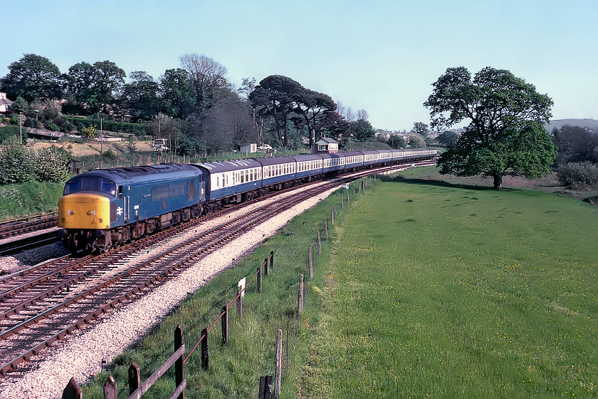 45041, Paignton-Newton Abbot ECS, Aller Junction 
 45041 'Royal Tank Regiment' worked to Paignton a little earlier and is now seen returning to Newton Abbot with the empty coaching stock composed entirely of twelve Mk.1 coaches. In the late afternoon spring sunshine, the train makes a fine sight as it passes Aller Junction, taken from the farm occupation bridge that, unfortunately, has now been removed as part of the A380 relief road construction. The new dual carriageway was opened in 2015 after numerous delays and passes immediately to the left of the train obliterating the allotments and the lovely trees behind the signal box. 
 Keywords: 45041 Paignton-Newton Abbot ECS Aller Junction Royal Tank Regiment