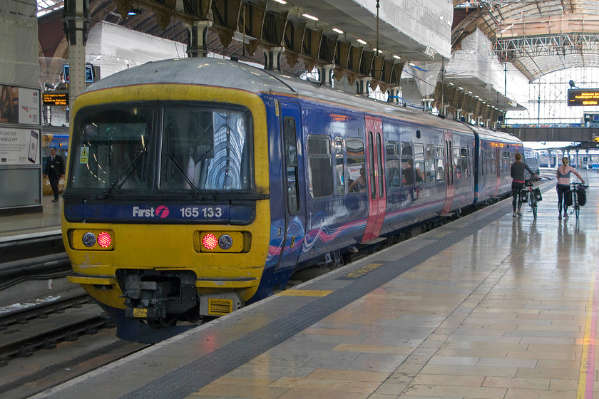 165133, GW 08.50 London Paddington-Oxford (1D19), London Paddington station 
 First Great Western's 166133 will soon leave Paddington with the 08.50 to Oxford. It is services such as this that will be run by smart new electric units in the coming few years as the wiring continues its relentless way westwards, if a lot slower than expected. Notice the reflection on the platform tiles of the couple walking their bikes! 
 Keywords: 165133 08.50 London Paddington-Oxford 1D19 London Paddington station First Great Western Turbo