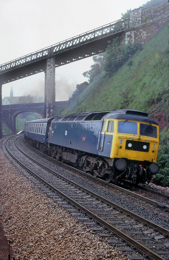 47082, 09.00 Paignton-Newcastle (1E36), Teignmouth 
 47082 'Atlas' accelerates away from Teignmouth station, the end of the down platform of which can just be seen, working the 09.00 Paignton to Newcastle service. With the verticals of the bridges appearing to be plumb the extreme camber of the track is clear to see rather than me, the photographer, having tipped the camera! Atlas survived in service until 2007 after being renumbered 47626 being cut up at EMR's facility at Kingsbury. Notice that somebody appears to have purloined the work's plate from just below the second man's window! 
 Keywords: 47082 09.00 Paignton-Newcastle 1E36 Teignmouth Atlas