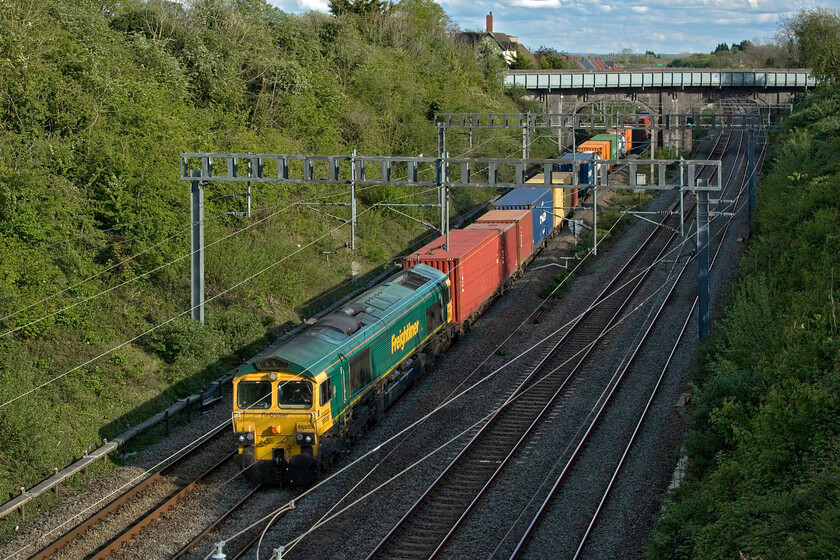 66538, 12.57 London Gateway-Garston (4M56, 29E), Hyde Road bridge 
 Heading north through Roade taken from the village's Hyde Road bridge 66538 is seen leading the 4M56 12.57 London Gateway to Garston Freightliner train. The bridge in the background with its rather ugly pedestrian parapet carries the the former A508 main road through the village. This road has now been downgraded and is a lot quieter due to the opening of the Roade bypass last September (2023). 
 Keywords: 66538 12.57 London Gateway-Garston 4M56 Hyde Road bridge Freightliner