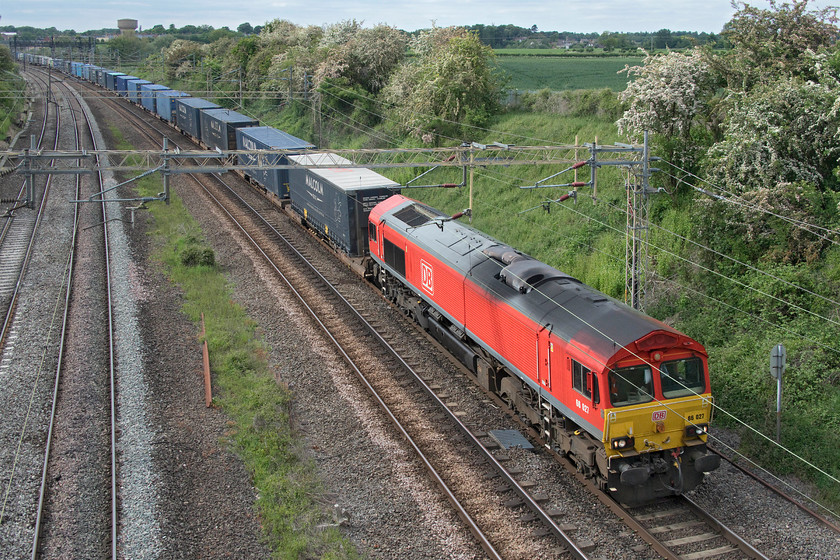 66027, 16.32 DIRFT-Grangemouth (4M49, 11E), Victoria bridge 
 The 4M49 16.32 DIRFT to Grangemouth stretches off into the distance at Victoria bridge just south of Roade. This train is not normally seen here as it usually heads north from Daventry but due to engineering works, it is taking a long and circuitous diversionary route via north London and the ECML. DB 66027 leads the train, as it will, all the way to Scotland arriving at breakfast time the following morning. 
 Keywords: 66027 16.32 DIRFT-Grangemouth 4M49 Victoria bridge Tesco