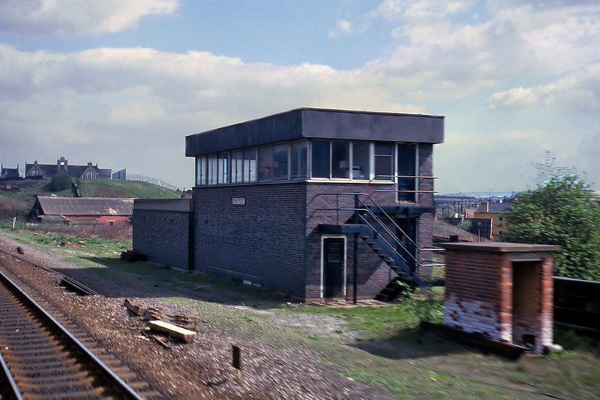 Brightside signal box (BR, 1965) 
 On leaving Sheffield station the next few miles of railway passed a manic and somewhat chaotic strip of heavy industry with a very distinctive smell permeating the train. Most of the industry was railway linked in some way or another with a number of minor junctions. Brightside signal box was located at the northern end of this industrial zone and was the point where a short section of line diverged to the east directly into Tinsley Yard. The box was a somewhat austere BR built structure dating from 1965 making it fifteen years old when this photograph was taken from a Mk.I droplight window as we passed. The school on the skyline is still in use as a 'children's centre' and nursery with the now closed Brightside station just a short distance beyond. This station was replaced by Meadowhall that is only a mile or so away from this location. 
 Keywords: Brightside signal box