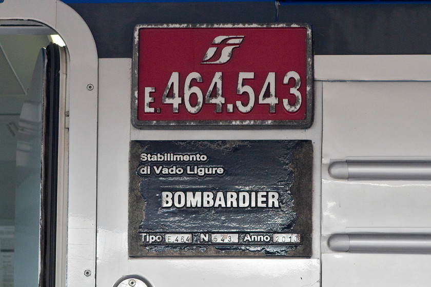 Nameplate & buildplate, 464.543, 17.28 Florence SMN-Grosseto (11727), Florence SMN station 
 UK train operators and leasing companies could take a leaf out of the Italian operators with regard to fitting number plates and buildplates. They are cast and painted as seen here on the side of 464.543 waiting at Florence SMN station with the 17.28 departure to Grosseto. Note that 464.543 was built by Bombardier during 2010 at their Vado Ligure plant that is situated near to the north western city of Savona. 
 Keywords: Nameplate buildplate 464.543 17.28 Florence SMN-Grosseto 11727 Florence SMN station