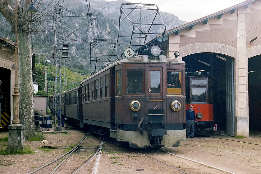 No. 2, unidentified Palma-Sller working, Sller station 
 With the mountains of the Serra de Tramuntana in the background, no. 2 arrives into Sller station with a service from Palma. Next to the 3ft gauge train is tram no. 1 in the tram depot that is part of the Tranva de Sller. The Sller railway was opened in 1912 (ironically on the same day that Titanic sunk!) in order to open up commerce, particularly the trade in citrus fruits, in the north of Majorca with the town of Sller being somewhat isolated by the mountains. 
 Keywords: No. 2 Palma-Sller working Sller station