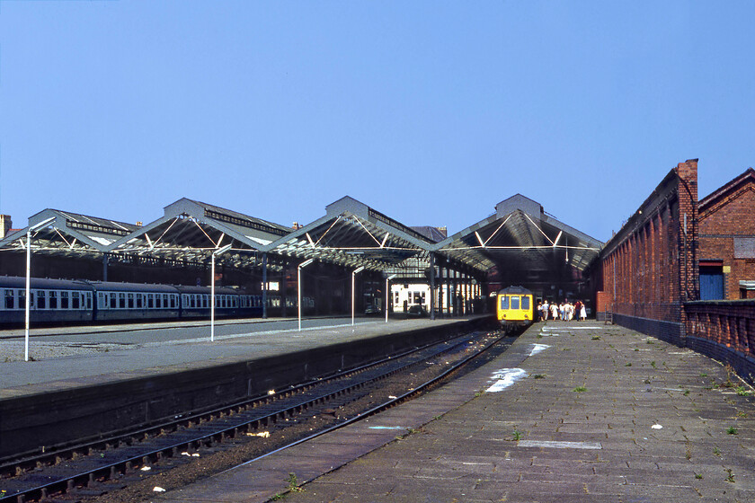 Class 108 DMU, 15.24 Llandudno Junction-Llandudno, Llandudno station 
 A wide view of Llandudno station revealing its platforms and the unusual central access road something that permitted Victorian carriages to access to the platforms in order that the town's visitors could be taken directly away to their hotels around the town. Notice the large glazed canopies that have been drastically reduced over the years with them once extending to a point level with the supporting wall to the right. The passengers seen have just arrived aboard the Class 108 DMU that has worked in as the 15.24 shuttle service from Llandudno Junction. 
 Keywords: Class 108 DMU 15.24 Llandudno Junction-Llandudno Llandudno station First generation DMU