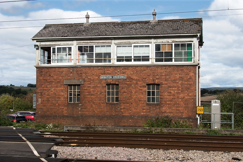 Bishton signal box (GW, 1941) 
 I last visited Bishton signal box in 1985 during the GWR 150 celebrations. It has changed very little in the intervening thirty-four years apart from replacement UPVC windows and the fitting of a reproduction GWR style cast nameplate, in 1985 it had no identification at all! It is good to see that the windows have been replaced with modern ones that replicate the original three panes over two arrangement as per most Great Western boxes. The box is a rare example of one that still has a wheel to operate the gates. In the case of Bishton, it remains a GWR style ship's wheel. The box is only manned from 06.00 to 22.00 so tall vehicles over one point seven metres high have to make a diversion to avoid the very low bridge that goes under the line. Notice the milepost showing one hundred and fifty-three miles next to the box. This is the distance from Paddington but rather than the direct route through the Severn Tunnel it is via Swindon, Stonehouse, Gloucester and Chepstow. 
 Keywords: Bishton signal box 1941