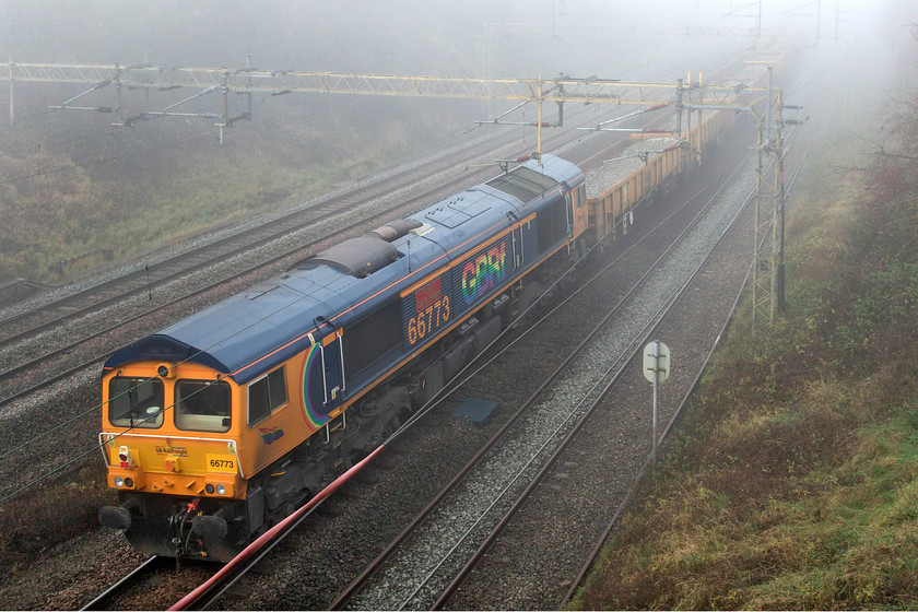 66773, 10.23 Watford South Junction-Bescot (6G51, 7L), Victoria bridge 
 66773 'Pride of GB Railfreight' dead in tow on the rear of the 10.21 Watford South to Bescot engineering train. Whilst the thick fog hung around all day, just the very slightest of weak sunshine has managed to penetrate it to illuminate the trailing cab end. The last time I saw this Class 66 it was in a somewhat different environment, see...... https://www.ontheupfast.com/p/21936chg/29595734804/x66773-10-35-bletchley-cemex-peak 
 Keywords: 66773 10.23 Watford South Junction-Bescot 6G51 Victoria bridge GBRf Pride of GB Railfreight