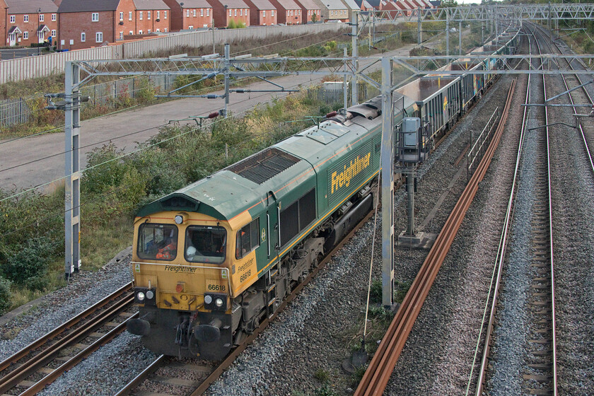 66618, 13.20 Willesden Yard-Tunstead (6H50, 5E), site of Roade station 
 66618 'Railways Illustrated-Annual Photographic Awards' leads the 13.20 Willesden Yard to Tunstead empty stone wagons running as 6H65. Stone trains are not particularly common on the WCML but with HS2 activity ramping up more freight of this type is now becoming far more frequent. Notice the tatty nature of the front end of this 2003 Class 66. The rust staining below the windscreens is an all too common issue with these locomotives most likely caused by poor sealing and a lack of attention paid to the surround flanges. 
 Keywords: 66618 13.20 Willesden Yard-Tunstead 6H50 site of Roade station Railways Illustrated - Annual Photographic Awards