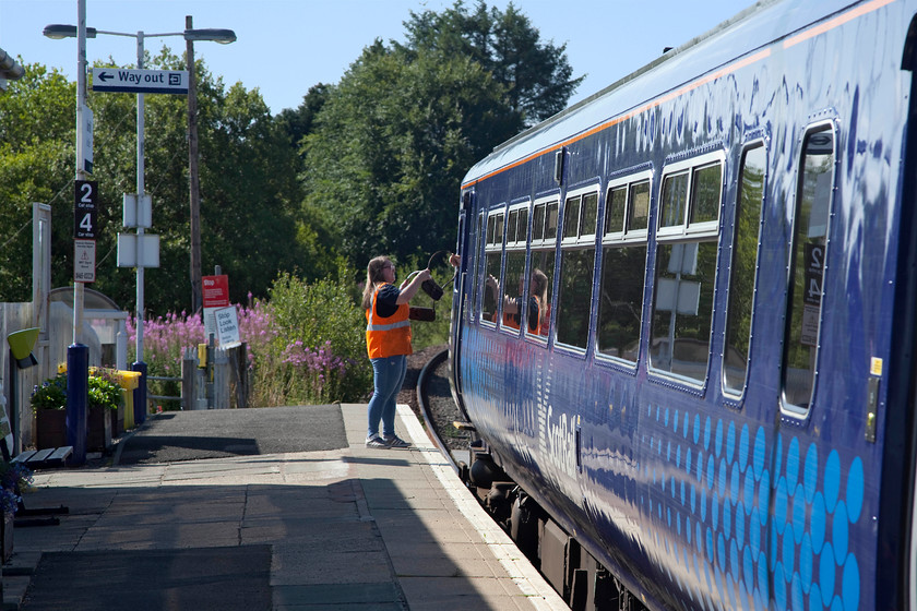 Exchanging the tablets, 156436, SR 08.08 Glasgow Central-Stranraer (1A10, RT), Barrhill station 
 The signalwoman at Barrhill exchanges the tablets with the driver of the 08.08 Glasgow Central to Stranraer being worked by 156436. Barrhill station is a pretty remote spot high up in the hills of south west Scotland, benign on day such as this, but in the depths of winter it would be a very different place! 
 Keywords: Exchanging the tablets 156436 1A10 Barrhill station