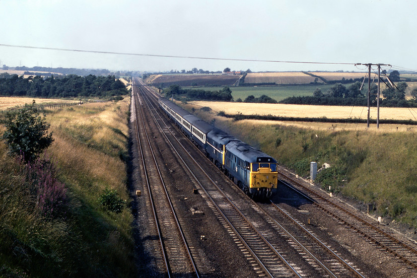 31411 & 31407, 13.29 Grimsby-London King`s Cross, Essendine TF043129 
 A single class 31 would not cut the mustard on the 13.29 Grimsby to King's Cross so the double-headed combination of 31411 and 31407 was utilised. Here at Essendine, at the southern end of Stoke Bank, the train is seen speeding southward. Notice the faded paintwork on 31411 following too many trips to the washer no doubt. Also, note the white stripe along the bodyside of 31407, indicating that it was a Finsbury Park locomotive. It was based at the north London depot all of it working life until transfer to Crewe Diesel in 1988. 
 Keywords: 31411 31407, 13.29 Grimsby-London King`s Cross Essendine TF043129