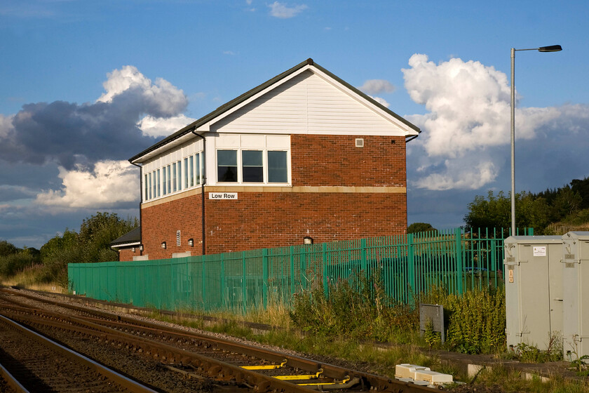 Low Row signal box (NR, 2009) 
 Low Row signal box was opened by Network Rail some five years ago replacing the original 1874 box at the diagonally opposite northwest corner. The box is a Network Rail designed gabled structure with a brick base and UPVC clad top with plenty of windows. The downstairs houses the very spacious locking room, which is all electrical but utilising mechanical relays. The upstairs houses an NX (Entrance Exit) Panel which has three-panel faces, of which only the centre one is used. According to the Branch Line Society who have visited the box the reason for its size - totally out of proportion to the area it presently supervises - is that the intention was for it to control the entire Newcastle to Carlisle line from two signal boxes, Prudhoe and Low Row. This has never happened, on the assumption that York Rail Operating Centre will eventually take over the signalling; it means that Low Row Box will have most likely a 'life' of less than twenty years. Until its closure on 05.01.59 there was a station on this site too with the level crossing behind where I am standing the site of a dreadful tragedy on 30.08.26. There was a peculiar arrangement whereby the station porter on duty opened the crossing gates when a vehicle wished to cross the line. On this day, for some unknown reason, he opened the gates to allow the passage of a charabanc over the line without checking his instruments and a Newcastle to Carlisle train ploughed into the vehicle killing nine persons including the errant porter. 
 Keywords: Low Row signal box Network Rail