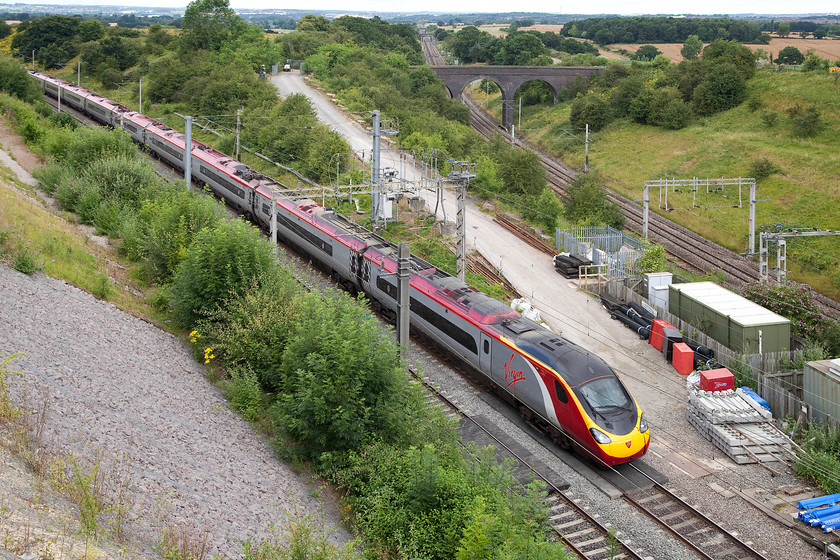 390115, VT 08.38 Liverpool Lime Street-London Euston (1A05), Blisworth Road bridge 
 From the lofty height of the Blisworth Road bridge just south of Northampton, 390115 'Virgin Warrior' heads south with the 08.38 Liverpool Lime Street to Euston. The recent engineering works to stabilise the cutting wall to the left involved it being totally cleared of vegetation that opened up the view. However, it is growing back at quite a rate at the base so once again, this view will disappear soon. 
 Keywords: 390115 08.38 Liverpool Lime Street-London Euston 1A05 Blisworth Road bridge