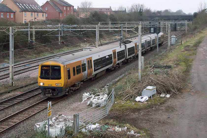 323208, 07.46 Soho sidings-Wolverton centre sidings (3E), site of Roade station 
 The weather was really pushing the camera to its limits on this ridiculously dull Saturday morning with the ISO being forced to 8000! At this level, there are inevitable digital noise issues to deal with. Rather than use Photoshop's bundled noise filter, that is actually pretty ineffective, I use Neat Image (https://ni.neatvideo.com/home) to deal with problems. Now on borrowed time with new units set to replace it, 323208 passes the site of Roade station as the 07.46 Soho sidings to Wolverton centre siding. It was going to Wolverton for attention with a balancing working coming the other way later in the morning. 
 Keywords: 323208 07.46 Soho sidings-Wolverton centre sidings site of Roade station West Midlands Trains