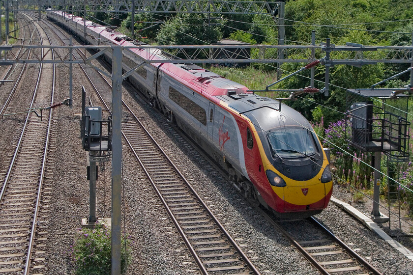 Class 390, VT 11.30 London Euston-Glasgow Central, site of Roade station 
 An unidentified eleven-car Class 390 Pendolino passes Roade working the 11.30 Euston to Glasgow Anglo Scottish service. The relay room half hidden by the uncontrolled vegetation is located where the original LNW signal box stood. This was a double-manned box and must have been a very busy and intense place to work. 
 Keywords: Class 390 11.30 London Euston-Glasgow Central site of Roade station VWC Virgin Pendolino