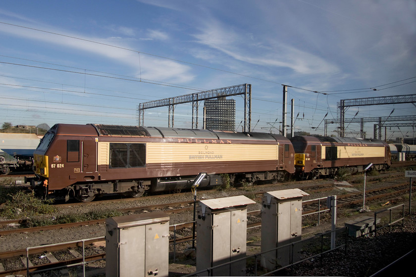 67021 & 67024, stabled, Wembley yard 
 I think that the retro. Pullman livery applied to the two class 67s dedicated to the Belmond operations looks very smart. I am, however, somewhat suprised that 67021 and 67024 are not named. A niced lined and properly cast nameplate would look very smart on the flanks and could be appropriate to the work that they are dedicated to undertake. Here, they catch some autumn sunshine stabled in Wembley yard. 
 Keywords: 67021 67024 Wembley yard