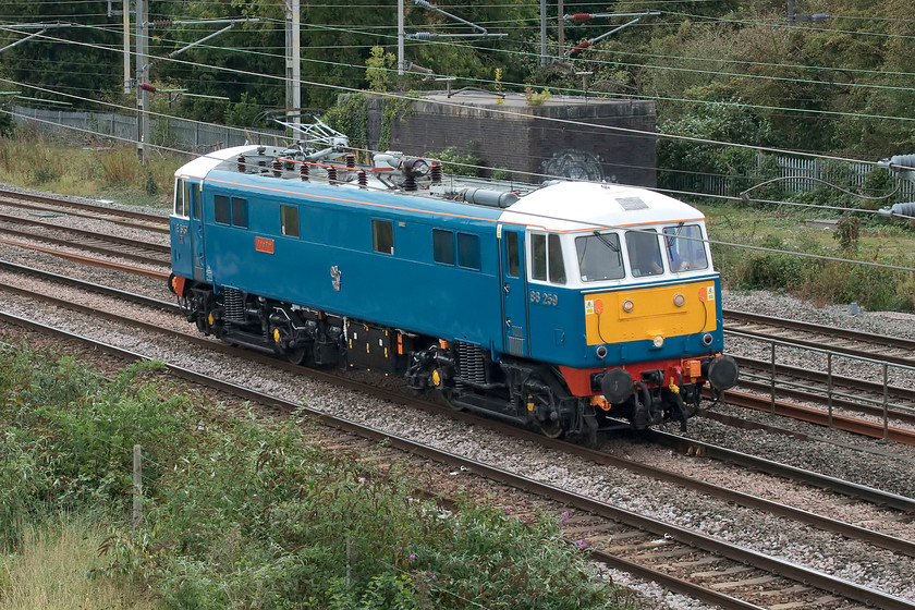 86259, 12.15 Acton Lane reception sidings-Rugby CS (0Z88, 60E), site of Roade station 
 Having undertaken railtour duties yesterday on 'The Cumbrian Coast Express' 86259 'Les Ross/Peter Pan' heads past the site of Roade's former station to its weekday home in Rugby carriage sidings. As the 0Z88 12.15 Acton Lane to Rugby, the light engine arrived sixty minutes early whereas all other down services were late, particularly service trains, leaving Euston that were delayed by the same amount. I believe that this issue was caused by overrunning engineering works within Euston station. 
 Keywords: 86259 12.15 Acton Lane reception sidings-Rugby CS 0Z88 site of Roade station Les Ross Peter Pan