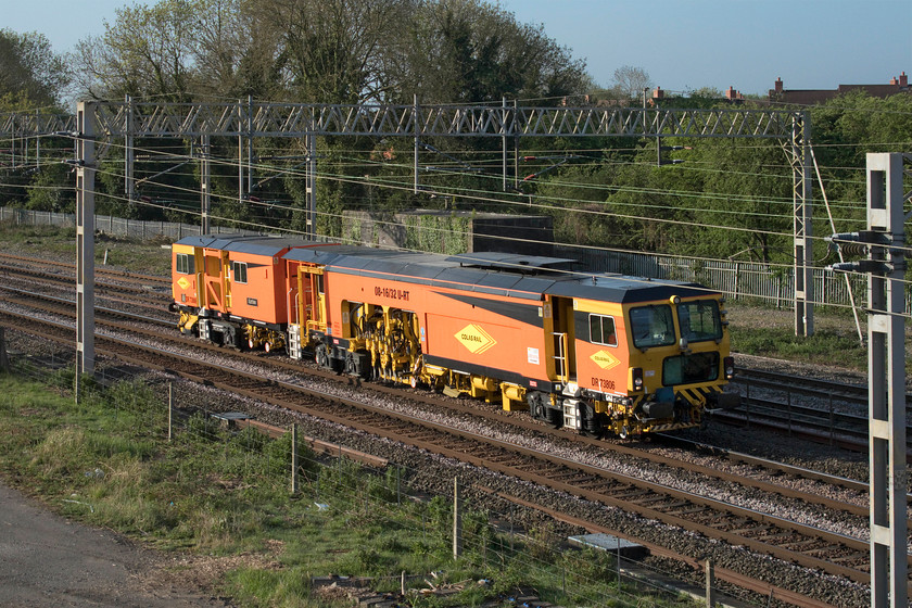 DR73806, 07.10 Bletchley Cambridge sidings-Rugby DED (18E), site of Roade station 
 Colas Rail operated Plasser and Theurer 08-16/32U-RT tamper DR73806 'Karine' brings a touch of orange as it passes the site of Roade's former station. It was making the relatively short journey from Bletchley's Cambridge sidings to Rugby. With its rather slow top speed control quite sensibly put the tamper on the Northampton line rather than the fast route via Weedon. 
 Keywords: DR73806 07.10 Bletchley Cambridge sidings-Rugby DED site of Roade station Karine Colas Rail-operated Plasser & Theurer 08-16/32U-RT Tamper