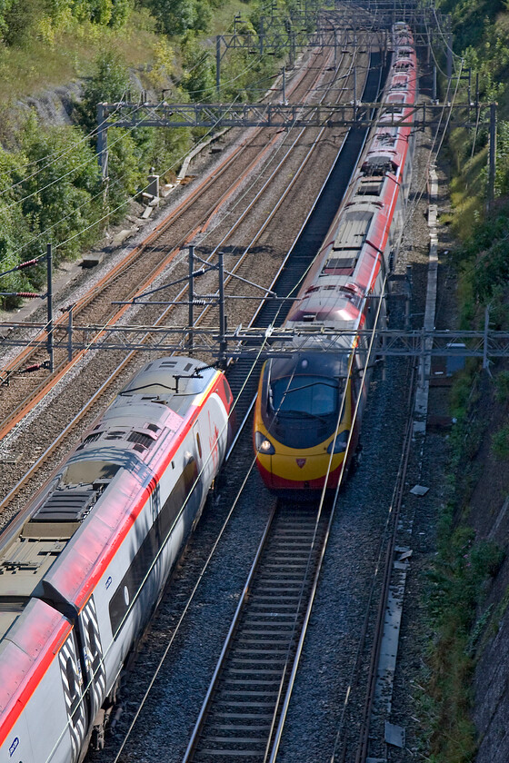 390008, VT 12.35 Manchester Piccadilly-London Euston (1A28) & 390135, VT 13.20 London Euston-Birmingham New Street (1G18), Roade cutting 
 With a probable approach speed of two hundred miles per hour 390008 Virgin King is about to pass 390135 City of Lancaster in Roade cutting. The former is working the 1A28 12.35 Manchester to Euston whilst the latter the 1G18 13.20 from Euston to Birmingham New Street. 
 Keywords: 390008 12.35 Manchester Piccadilly-London Euston 1A28 390135 13.20 London Euston-Birmingham New Street 1G18 Roade cutting Virgin Pendolino Virgin King City of Lancaster