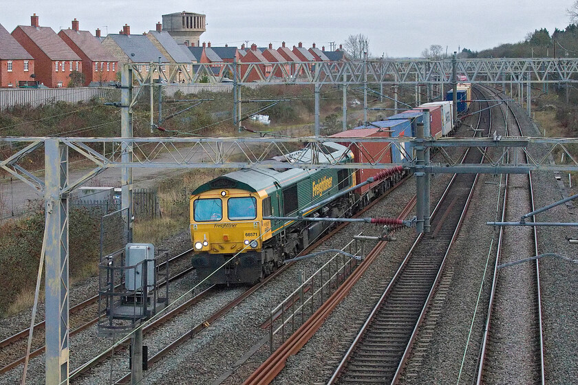 66571, 11.16 London Gateway-Trafford Park (4M58, 3E), site of Roade station 
 Taken somewhat blind over the parapet of the footbridge at the site of Roade's former station 66571 passes working the 4M58 11.16 London Gateway to Trafford Freightliner. It was travelling fairly slowly on caution as it was right behind the late-running 5Q95 Class 323 drag seen in the previous photograph. 
 Keywords: 66571 11.16 London Gateway-Trafford Park 4M58 site of Roade station Freightliner