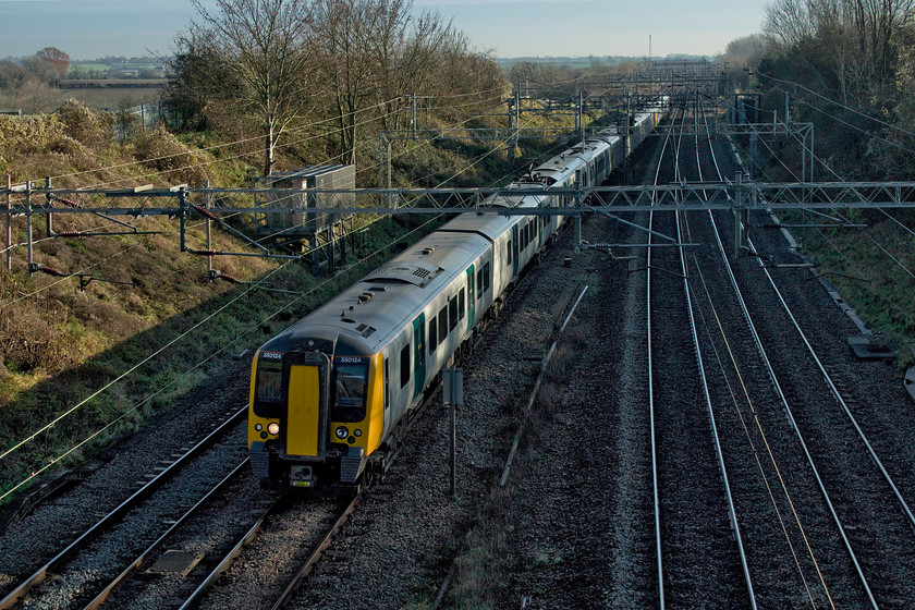 350124, 350257 & 350106, LN 12.24 London Euston-Northampton (2N65, 1E), Victoria bridge 
 The sun is just managing to catch the sides of the 12.24 Euston to Northampton worked by 350124, 350257 and 350106 as it passes Victoria bridge just south of Roade. Railway photography is tricky at this time of the year with exposure settings always having to be thought about carefully to help manage the extreme contrast created by the low light. I tend to expose for the lighter areas and bring the shadows back in Photoshop. My reasoning is that there is always detail to be found within the darker areas of digital images but in overexposed areas most is lost. However, the downside of this method is that digital noise can become a problem in the darker areas when forcing them back so it's all about a compromise! 
 Keywords: 350124 350257 350106 12.24 London Euston-Northampton 2N65 Victoria bridge