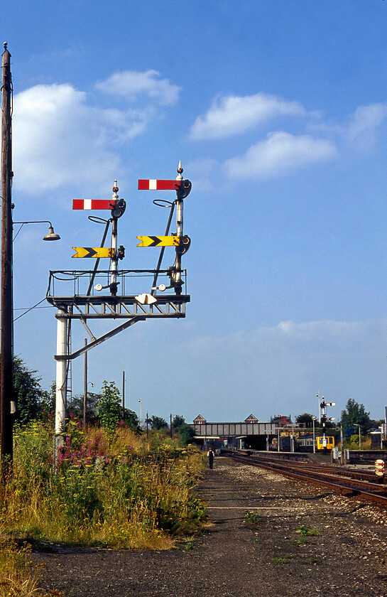 Down bracket signal, Wrexham station 
 Quite how Graham and I (he is seen with his back to me returning to the station) managed to simply wander off the end of Wrexham General station and take this photograph remains a mystery to me! Either way, it does show a rarely seen face-on view of Wrexham's down starter bracket signal. Notice that severe track rationalisation has meant that a huge gap has opened up between where the signal is standing and the running lines that it controls. A DMU sits in Wrexham station awaiting its next duty, unfortunately, my very detailed notes from the time make no mention of this that seems very remiss of me looking back some forty years on! 
 Keywords: Down bracket signal, Wrexham station