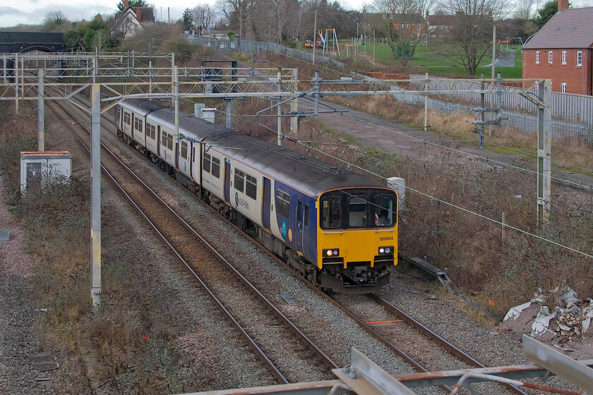 150004, 10.32 Neville Hill TMD-Wolverton Centre Sidings (5H70, 29E), site of Roade station 
 Now approaching its fortieth birthday Northern's 150004 passes Roade as the 5H70 10.32 Neville Hill to Wolverton Centre Sidings transfer. The unit will be in the works for some weeks while various repairs and updates take place before returning north again. 150004 is one of the very early units that was built as a two-car set that was later re-configured to three cars. To date, this is my only photograph of this unit. 
 Keywords: 150004 10.32 Neville Hill TMD-Wolverton Centre Sidings 5H70 site of Roade station Northern