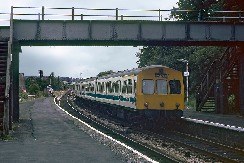 Class 101 DMU, 11.35 Leeds-Morecambe, Wennington station 
 I always thought that this revised livery applied to the class 101 DMUs (and a number of their counterparts) was very smart. However, it was not always the most practical colour with huge swathes of white bodyside for the BR depot staff to keep clean. At Wennington, an unidentified member of the class passes through the station forming the 11.35 Leeds to Morecambe service. This scene is very similar today with the same footbridge still in use. The only major difference is the loss of the semaphores when the signalling was removed in 2006. 
 Keywords: Class 101 DMU 11.35 Leeds-Morecambe Wennington station