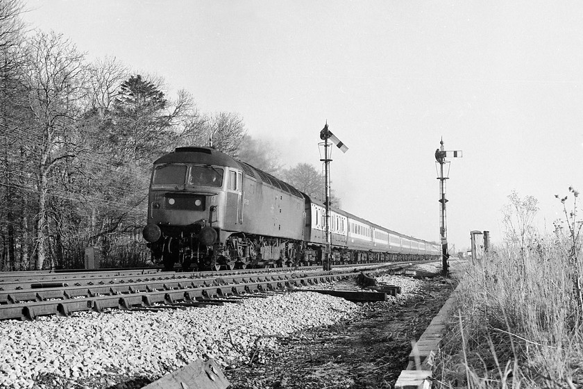 47530, unidentified down working, Woodborough SU096596 
 A lovely picture of 47530 at full chat past Woodborough's down home signals with an unidentified express for the West Country. Woodborough is a small village in Wiltshire that once boasted a station, a signal box and some sidings. It still retains an up and down passing loop today and two short sidings often used to store track machines but all else has gone. Careful study of the picture reveals a portent of things to come as I have cunningly hidden one of the new colour lights behind the signal post for the down loop. The semaphores here at Woodborough along with those at Lavington and the up main advanced starter and down distant of Heywood Road (Westbury) were all decommissioned the following weekend to when this picture was taken as the whole area came under the control of the Reading Panel. 
 Keywords: 47530 down working Woodborough SU096596