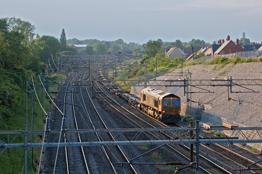 66786, 15.04 Birch Coppice-London Gateway (4L68, 48L), Ashton Road bridge 
 A photographic cop! 66786 'CURC Cambridge University Railway Club Founded by Junior Members 1911' passes Roade leading the evening 15.04 Birch Coppice to London Gateway service that was running nearly and hour late at this time. It appears that the camera, in trying to cope with the extreme contrast has done something strange to the sky. However, it has actually rendered it correctly as the day-long intense blue sky was being encroached upon by some grey haze moving in from the northwest. 
 Keywords: 66786 15.04 Birch Coppice-London Gateway 4L68 Ashton Road bridge GBRf CURC Cambridge University Railway Club Founded by Junior Members 1911