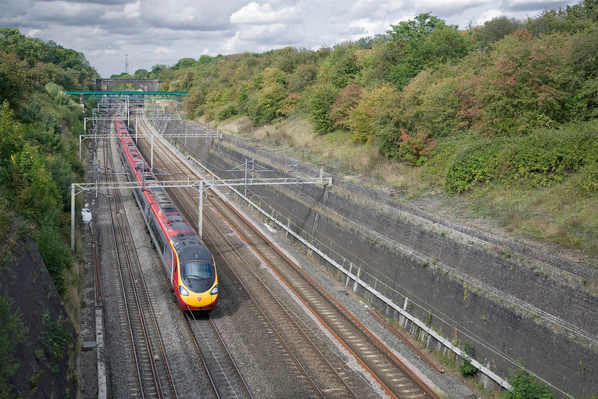 390018, VT 12.35 Manchester Piccadilly-London Euston (1A28), Roade cutting 
 A deliberate wide view of Roade cutting reveals it in all of its glory! 390018 passes through it heading south forming the 1A28 12.35 Manchester Piccadilly to Euston Virgin service. Notice the heavily clouded sky that makes it all the more surprising that most of the photographs taken in the last hour have been in strong sunshine! 
 Keywords: 390018 12.35 Manchester Piccadilly-London Euston 1A28 Roade cutting Virgin Pendolino