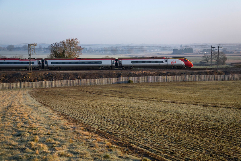 Class 390, VT 06.10 Manchester Piccadilly-London Euston (1A05), Blisworth 
 An unidentified Virgin Pendolino heads south past Blisworth located between Roade and Weedon on the southern WCML. It is working the 1A05 06.10 Manchester to Euston service, the first up working from Piccadilly of the day. I chose a fairly wide-angle view to show the frosted tillering wheat in the field dropping down towards the railway and the dreaded palisade fencing. 
 Keywords: Class 390 06.10 Manchester Piccadilly-London Euston 1A05 Blisworth