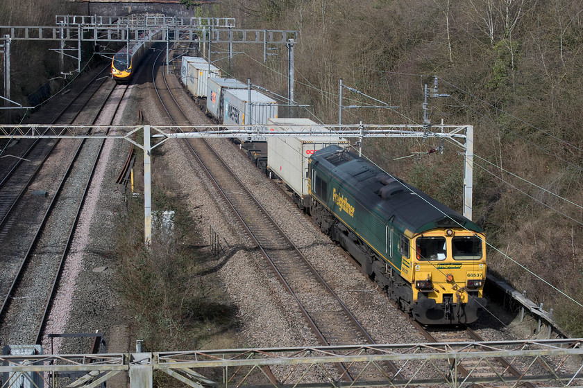 66537, 09.58 Basford Hall-Felixstowe North (4L79) & 390138, VT 10.47 Liverpool Lime Street-London Euston (1A25, 1L), A508 road bridge, Roade 
 66537 brings the 09.58 Crewe Basford Hall to Felixstowe Freightliner through Roade Cutting about to pass under the A508 road bridge in the village. This was a very lightly loaded train with just the five boxes seen here, the rest was just a procession of empty flats. Having heard an item on the radio in the week from the Felixstowe terminal this situation is a refection of our current trading situation. The vast vessels arriving and the trains leaving the terminal are packed with full boxes of goods. Meanwhile, many of the trains arriving are lightly loaded or even carrying empty boxes to then be taken away on the vessels. This is a situation that the chancellor will not be at all happy about and one that BREXIT will or will not change for the better depending on your dogma! The train is about to be overtaken by 390138 'City of London' working the 10.47 Liverpool Lime Street to Euston service. 
 Keywords: 66537 09.58 Basford Hall-Felixstowe North 4L79 390138 10.47 Liverpool Lime Street-London Euston 1A25 A508 road bridge, Roade