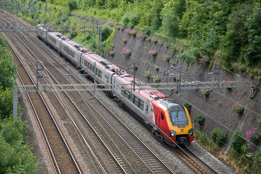 Class 221, VT 10.10 London Euston-Chester (1D84), Roade cutting 
 An unidentified class 221 tilting Voyager whisks its passengers through Roade cutting as begins the double track section of the route as far as Rugby. The tilting mechanism of the 10.0 Euston to Chester service will be working hard to keep things comfortable for the passengers on this eighteen-mile stretch of winding track with plenty of reverse curves. 
 Keywords: Class 221 10.10 London Euston-Chester 1D84 Roade cutting Virgin Trains Voyager